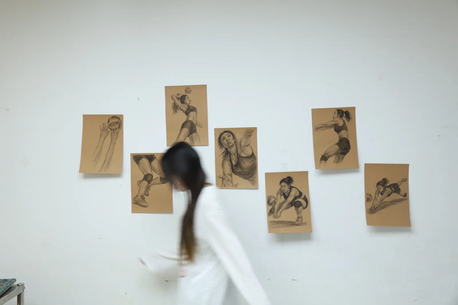Annie hanging volleyball figure drawings on a gallery wall